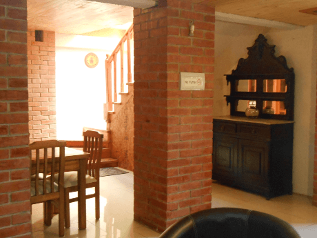 <img src="sala-comun.jpg" alt="Salón compartido con sillones de cuero, muro de ladrillo visto y decoración colonial">